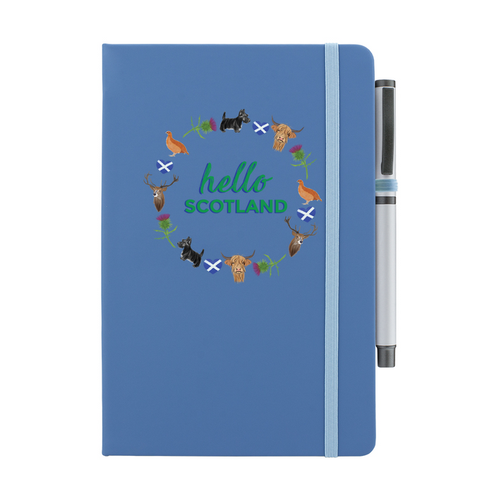 Denim Blue notepad with pen features a circular prints of Scottish Icons including the St Andrews Flag in a loveheart shape, a pheasant and a deer. A matching strap closes on the right hand side.