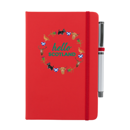 Red notepad with pen features a circular prints of Scottish Icons including the St Andrews Flag in a loveheart shape, a pheasant and a deer. A matching strap closes on the right hand side. 