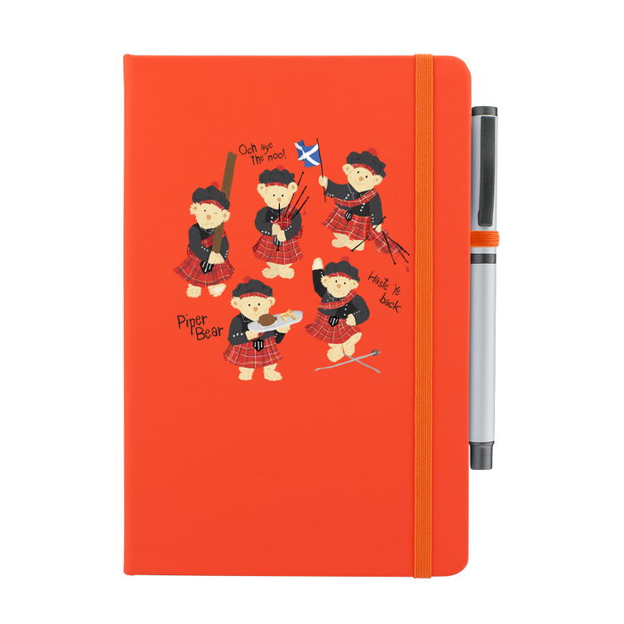 A beautiful designed orange notebook featuring a vibrant illustration of dancing piper bears in red and black, playing bagpipes joyfully. An orange strap closes over the right hand side with a matching pen.