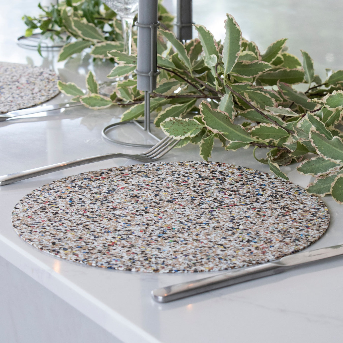 Tablemats made from beach waste are placed on a table with cuttlery and greenery around it 