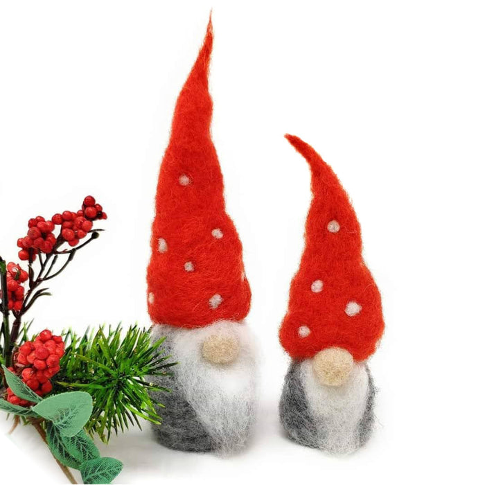 Two felted nordic gnomes with some festive greenery against a white backdrop
