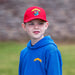 Child wears a blue hoodie and red cap, both featuring a knight on a horse. 