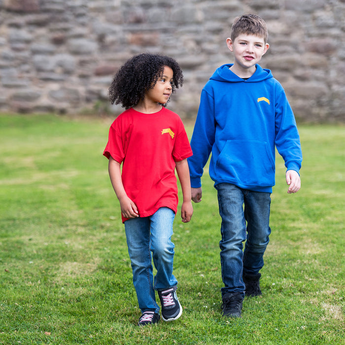 Two children walk on frass wearing dark jeans. One wears the Red Scotland T-Shirt whilst the other wears the Blue Knight Hoodie. 