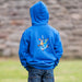 Person stands in front of a brick wall facing away to show the knight design on the back of a blue hoodie.