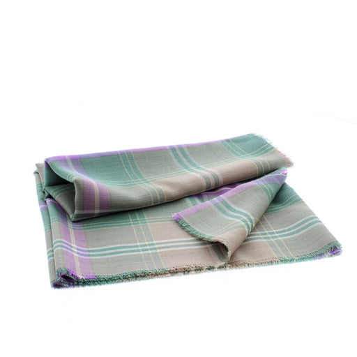 A fine wool woven scarf in a green and purple tartan is neatly folded. 
