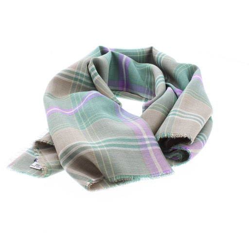 A fine wool woven scarf in a green and purple tartan is laid out to mimic how it would sit around a neck. 