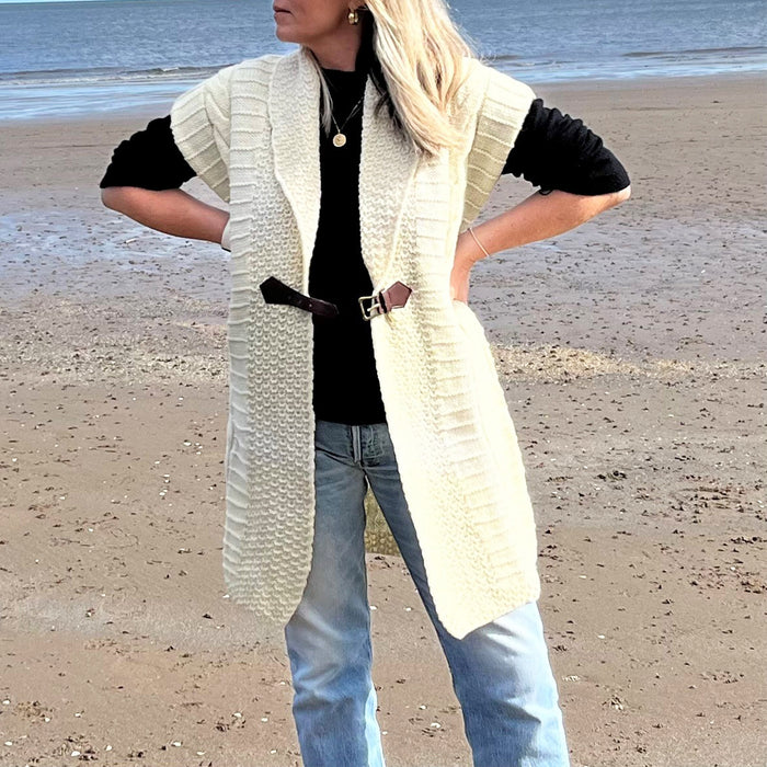 Person standing on a beach wears the buckle cardigan in cream 