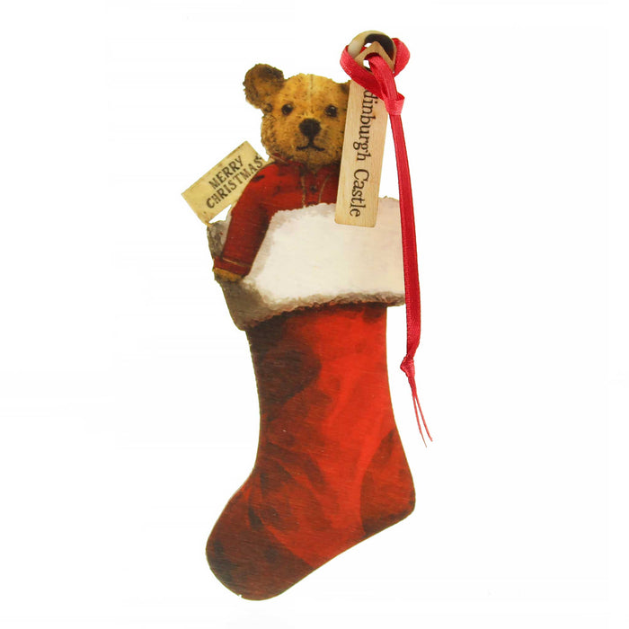 Small wooden tree decoration in the shape of an old fashioned Teddy Bear. The teddy is popping out of a Red Stocking and has a red ribbon for hanging. A small tag on the ribbon reads 'Edinburgh Castle'. 