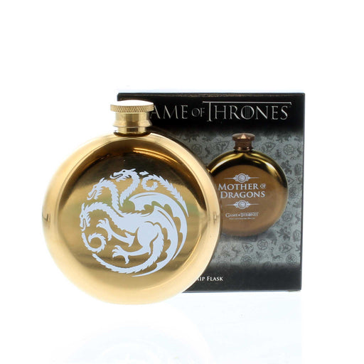 Gold circular tin flask with box behind. The flask is an official Game of Thrones piece with an image of a 3 headed dragon printed on the back  in white. 