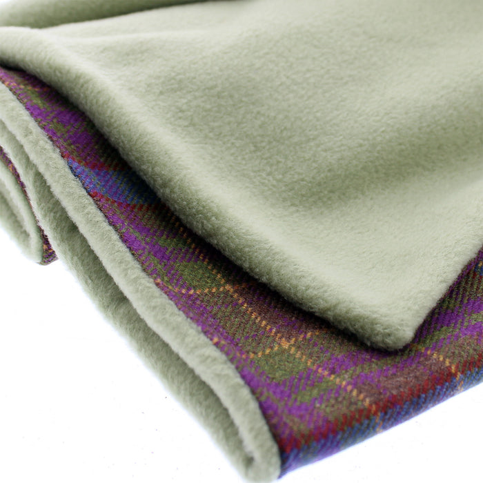 Tartan Scarf in a green, blue and purple weave that is exclusive to the local Grassmarket Tartan. The scarf is folded neatly to show the reverse side which is compiled from a plush green fleece. 