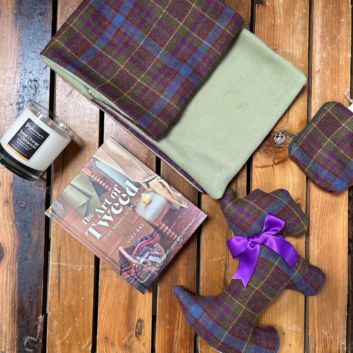 Selection of the Grassmarket Tartan products laid on a wooden floor with candles and a tweed book 