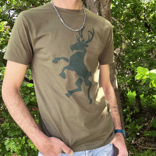 Person wears a army green t-shirt with a dark green stag print. The background is trees lit by the sunshine.