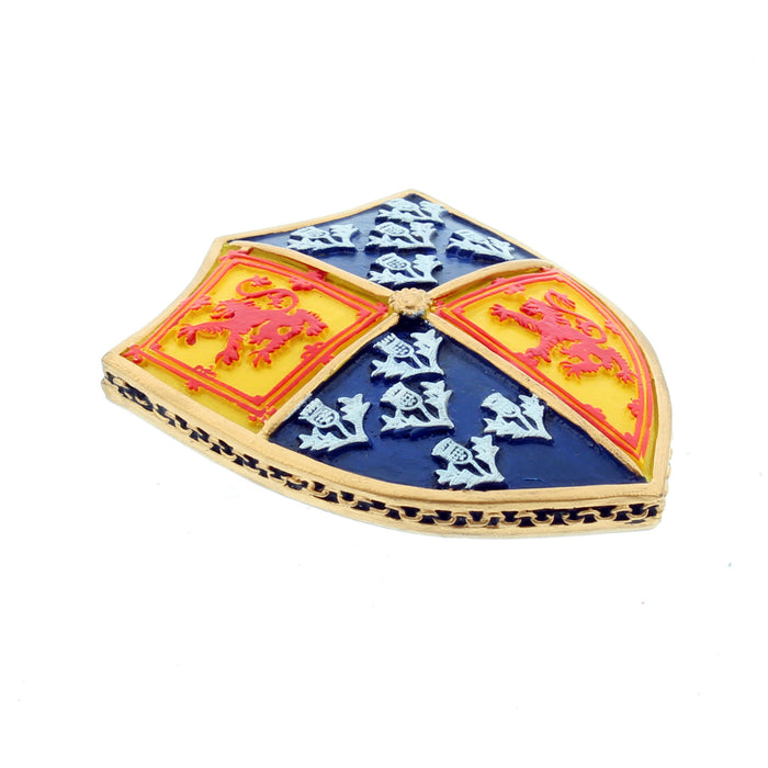 A fridge magnet in the shape of a shield features the Lion Rampant and the Scottish Thistle. A gold trim surrounds the edges.  The magnet is laid flat where the gold sides are shown.