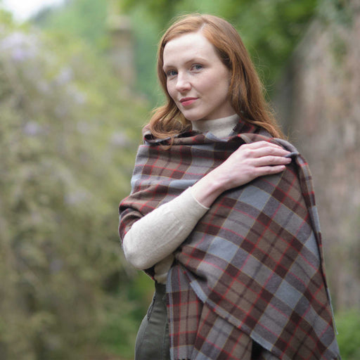 Person on a bricked lane wraps themselves in the Outlander Fraser Tartan Stole. 