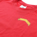 Close up of the front of the red t-shirt which features a yellow label reading SCOTLAND