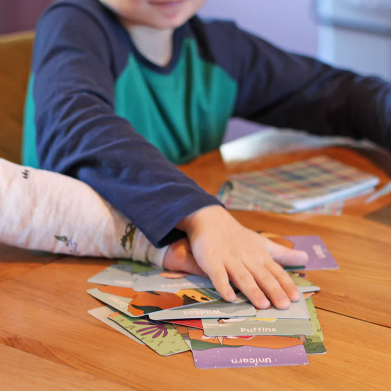 Children's hands are seen on top of a pile of cards actively playing Scotland Snap.  - Image