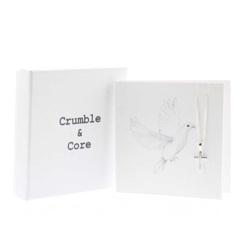 White card with a print of a white dove in flight. The card has a silver cross chain hanging from the  in the top right hand corner. To the left is a white kraft box with the text 'Crumble & Core'. 
