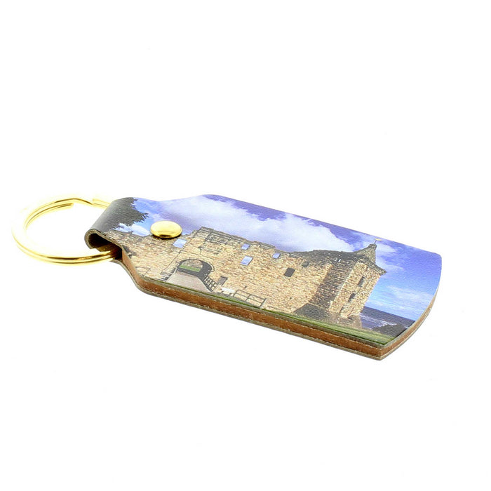 Rectangle shaped leather keyring with gold ring hardware features a printed photograph of the St Andrews Castle against a blue sky. 