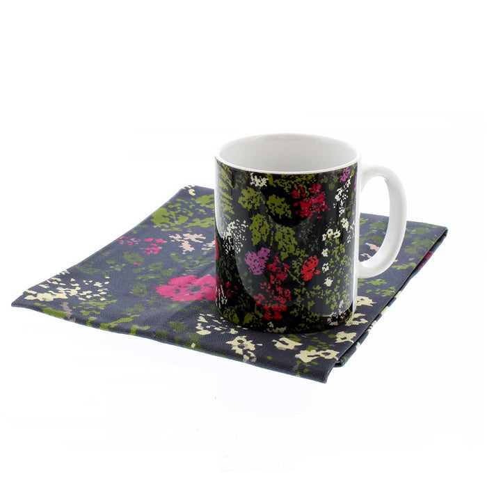 The Tapestry print tea towel folded with it's matching mug placed on top.
