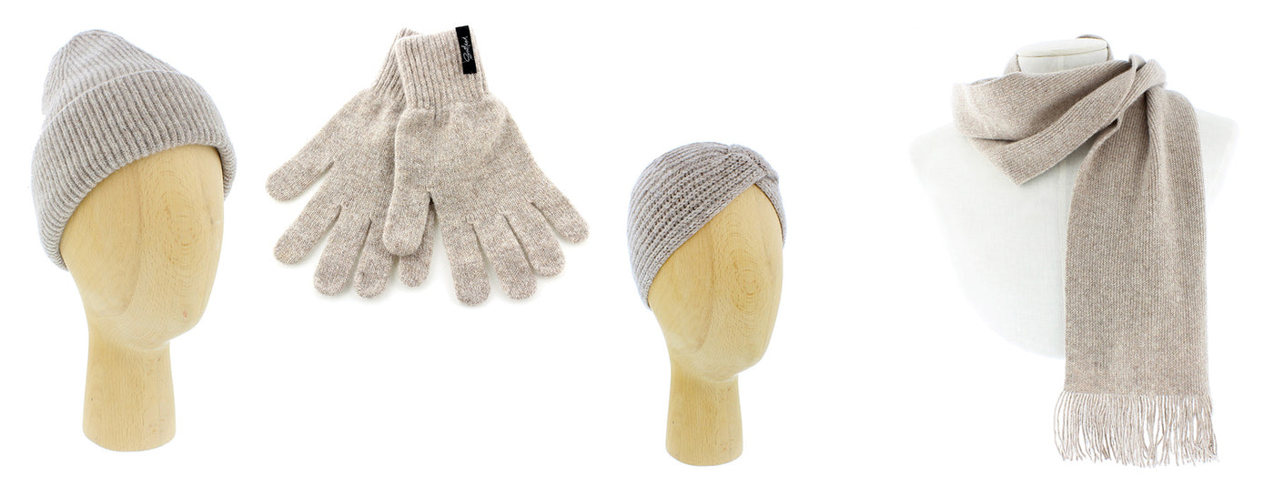 The Castle cosies range consists of both a hat and headband displayed on a wooden mannequin head, a scarf displayed on a white mannequin bust and a pair of matching gloves. The range is coloured in a neutral tone. 