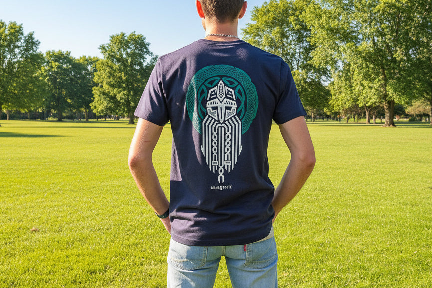 person stands facing away wearing a navy t-shirt. The bacl of the t-shirt show a large print of a viking and a celtic design in green and white.  - Image