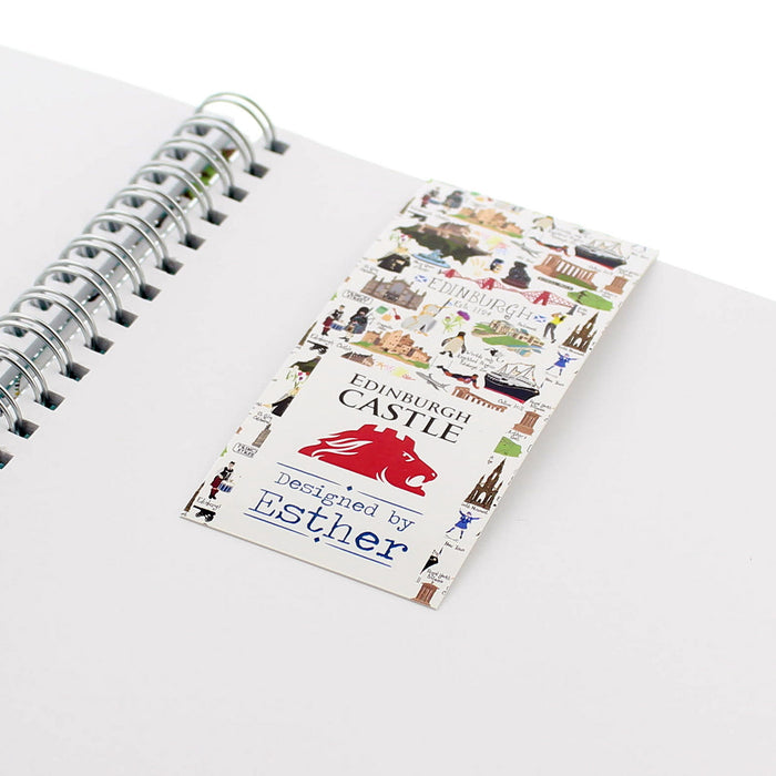 White magnetic bookmark shown in a white notepad. The bookmark features many of Edinburgh's landmarks. 