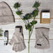 Knitted Hat, Gloves and Headband in Stone laid on a wooden floor next to some thistles, a candle and Siabann Handcream