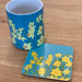 Daffodil printed coaster and mug placed on a wooden kitchen work top