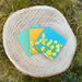 trio of spring inspired floral coasters placed on a wooden stump in a grassy field. 