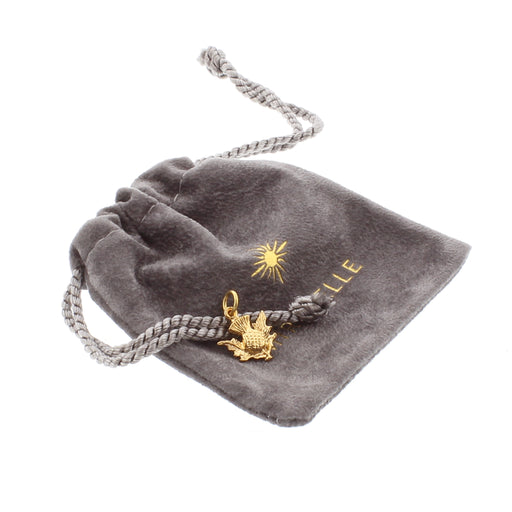 Small Gold Thistle Charm placed on a grey drawstring velvet pouch.