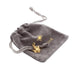 Small Gold Thistle Charm placed on a grey drawstring velvet pouch.