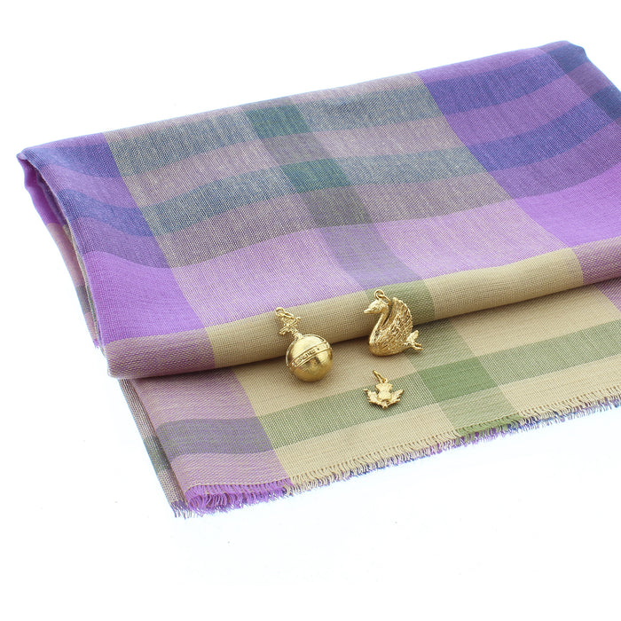 Selection of gold charms placed on a purple and green tartan 'Coorie' scarf include the Orb, Swan and small thistle.