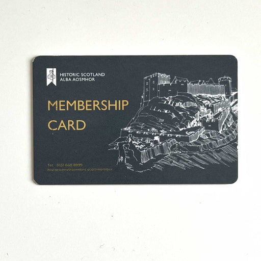 The Official Historic Scotland Membership card. The dark grey card features the official logo in the top left corner, and image of  castle on a hill to the right and the text in yellow reads 'Membership Card' with the company phone number and website below. 