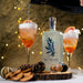 Festive cocktails using NcNean Botanicla Spirit are poured into glasses surrounded by fairy lights and dried festive acorns