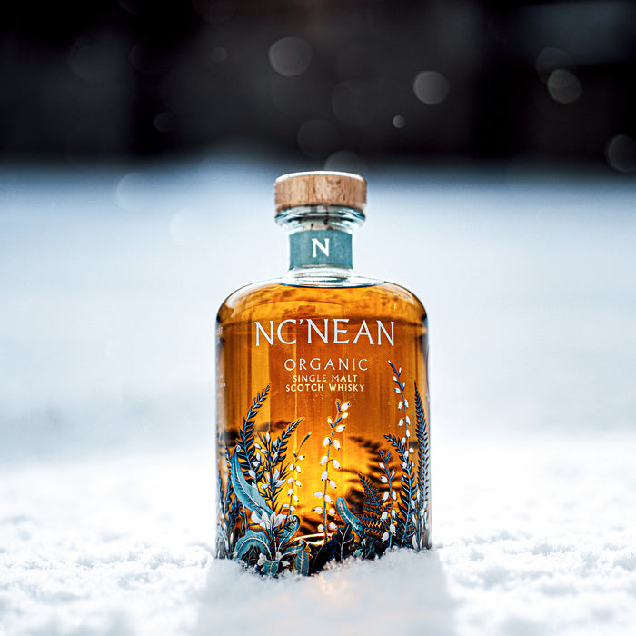 Bottle of NcNean Organic Single Malt Whisky sitting in the snow 