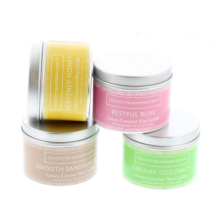Bright coloured candle tins featuring honey, rose, sandalwood and coconut scented candles.