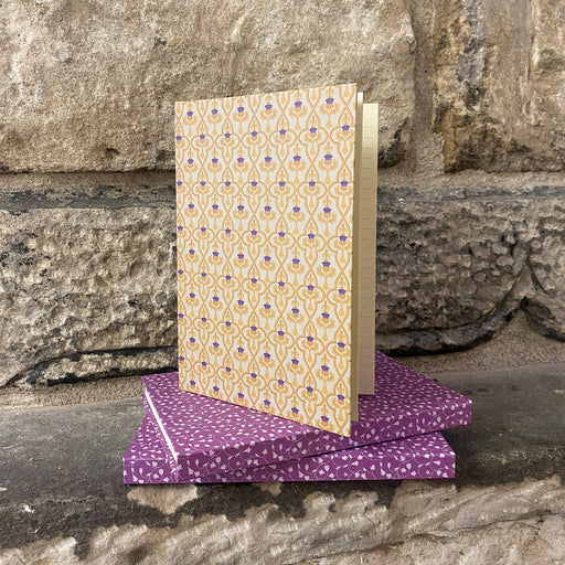 Thistle and Tulip Print notebooks on a stone wall 