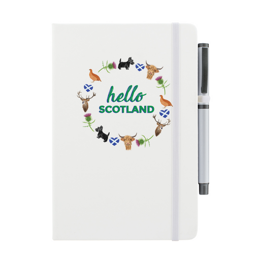 A beautiful designed white notebook with the words 'Hello Scotland' in green, featuring elements of Scottish culture and scenery. A white strap closes over the right hand side with a matching pen.