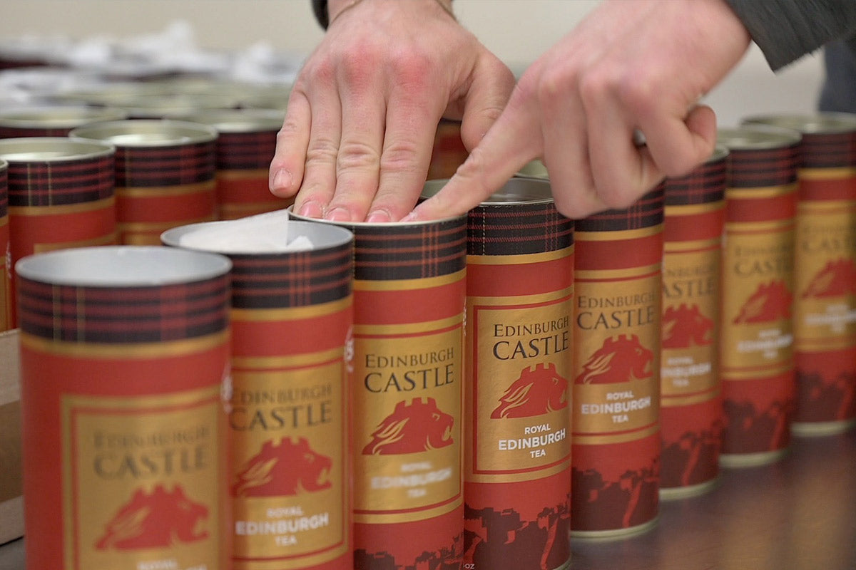 edinburgh castle tea being produced and teabags put into tins with hands pressing down on a lid