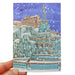 snowy illustration of edinburgh castle on christmas card front with robin perched on a large fountain in front of image. card is held by hand with fingers visible bottom left.  - Image