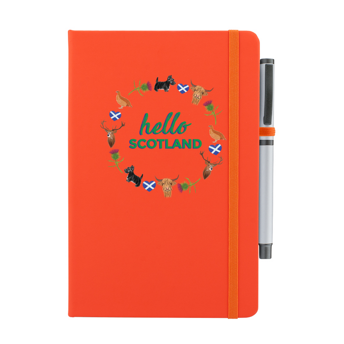 A beautiful designed orange notebook with the words 'Hello Scotland' in green,  featuring elements of Scottish culture and scenery. An orange strap closes over the right hand side with a matching pen.