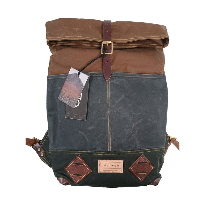 A terrae magnum roll-top canvas backpack in brown and dark gray-green, featuring dark brown leather straps, a brass buckle, and diamond-shaped leather patches on the front. - Image