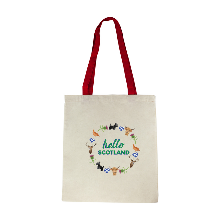 Cotton tote shopper with red straps features a circular design of scottish icons including the St Andrew's flag, a deer, a scottie dog, a thistle flower, a pheasant and a highland cow. Inside the design are the words 'Hello Scotland' in a green font. 