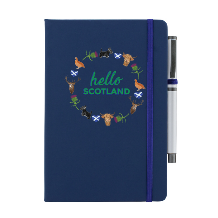 A beautiful designed navy notebook with the words 'Hello Scotland' in green,  featuring elements of Scottish culture and scenery. A navy strap closes over the right hand side with a matching pen.