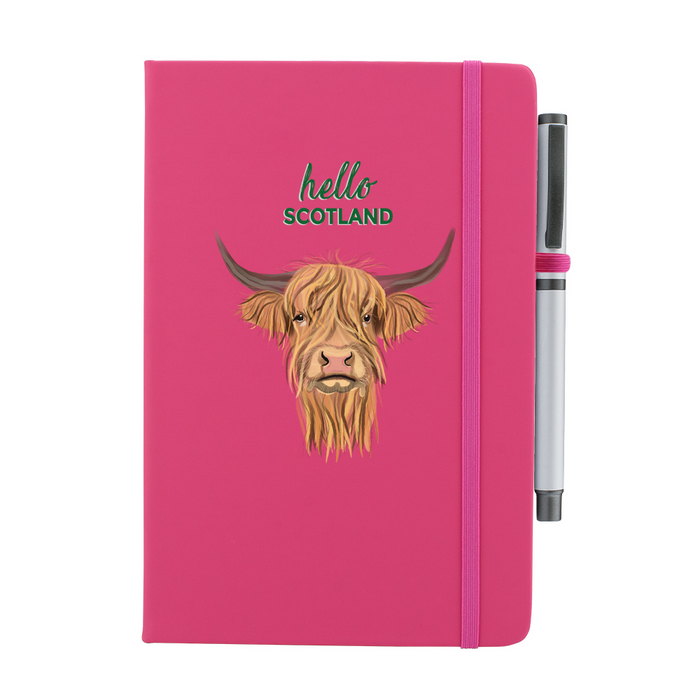 Pink soft feel note pad with a highland cow motif. the text above reads 'hello SCOTLAND' and comes with a silver pen attached.
