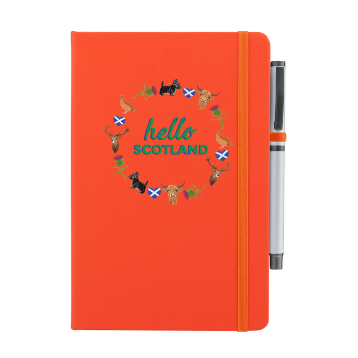 Orange notepad with pen features a circular prints of Scottish Icons including the St Andrews Flag in a loveheart shape, a pheasant and a deer. A matching strap closes on the right hand side.