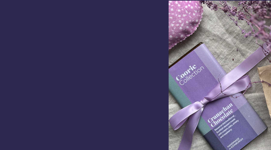 A bar of chocolate in purple wrapping is laid next to some dried lavender and a tulip printed heart pouch.