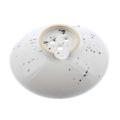 light coloured circular soap dish with a black paint splash effect pattern, view from the bottom 
