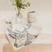 stag linen tea towel shown drapped on edge of table with cups and jug above and green plant in glass vase