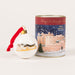 A white Christmas ornament with a red ribbon and gold cap stands beside a cylindrical tin. The tin features a winter scene with a castle under falling snow and reads 'Merry Christmas from France' and '2026 BAUBLE LIMITED EDITION'. - Image